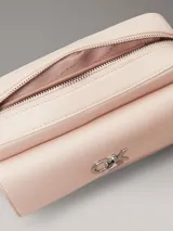 Cartera cruzada Calvin Klein de color rosa pálido, con solapa frontal y logo metálico 'CK' plateado. Posee correa de cadena plateada.