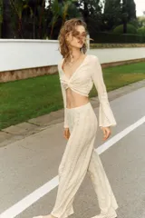 Pantalón palazzo color crudo, de tiro alto con cintura elástica y calado con motivos geométricos.