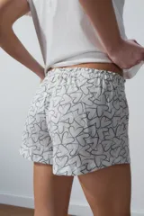 Conjunto de pijama corto blanco, compuesto por una remera de algodón con estampado de texto en el pecho y un short con estampado de corazones.