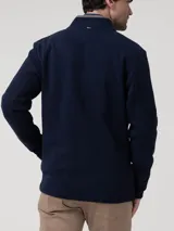 Buzo de hombre color azul marino, tejido de punto, con cuello alto y cierre frontal. Presenta un forro interior de cuello en gris claro.