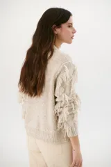 Sweater color arena de tejido de punto con cuello redondo y mangas largas con flecos.
