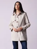 Gabardina impermeable color beige, marca Weatherproof, con abertura central con botones, bolsillos delanteros y capucha desmontable.