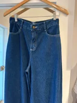Pantalón de jean azul oscuro de corte ancho con costuras blancas a la vista.