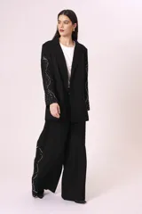 Blazer negro con mangas de encaje bordado y solapas clásicas.