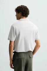 Polo de piqué color crudo, corte regular fit, cuello solapa con cierre de botonadura y mangas cortas.