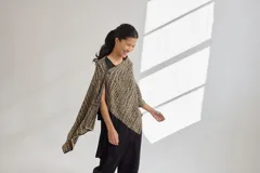 Chal con diseño jacquard en tonos beige y negro, de forma rectangular y caída fluida.