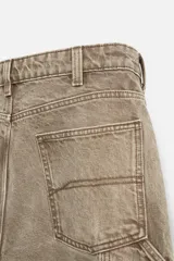 Pantalón color marrón con efecto lavado, corte relaxed fit, cinco bolsillos, aplicación de tira y bolsillo multifunción en perneras, cierre frontal con cremallera y botón.