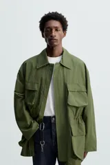Parka verde militar de corte relaxed fit confeccionada en tejido técnico ligero. Cuello solapa y manga larga. Bolsillos de plastrón con solapa en delantero. Cintura ajustable en interior. Cierre frontal con cremallera oculta por solapa con botones a presión.