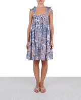 Vestido corto con estampado floral en tonos azul, rosa y blanco. Tiene breteles con lazos y falda con volantes.