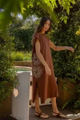 Vestido largo color marrón con bordado floral blanco en el lateral. Corte recto y mangas cortas.