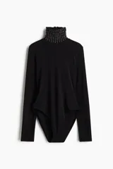 Body negro de manga larga con cuello alto adornado con tachas metálicas y strass.