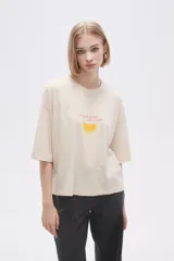 Remera color crema con estampado de limón y texto en color naranja.