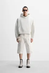 Sudadera color crudo, estilo hoodie, corte boxy, con capucha, manga larga, bolsillo tipo canguro y terminaciones en rib.