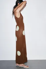 Vestido midi de tejido de punto color marrón, sin mangas y con cuello redondo. Presenta un estampado de lunares grandes en color crema/blanco roto.