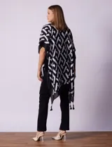 Kimono tejido con estampado geométrico en blanco y negro, ruedo con borlas y composición 100% poliéster.