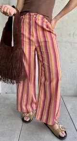 Pantalón de lino a rayas verticales en tonos rojo, naranja, marrón y rosa, con cierre y botón, y dos bolsillos laterales.