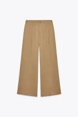 Pantalón palazzo color beige de tiro alto, con bolsillos delanteros y pernera ancha.