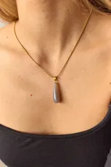 Collar dorado con cadena fina y dije colgante en forma de lágrima de piedra natural azul con vetas blancas.