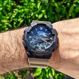 Reloj CASIO G-SHOCK GA110TU-1A5DR con caja negra y correa beige de resina. Esfera analógica-digital de 52mm con detalles en naranja y blanco. Resistente al agua hasta 200 metros.