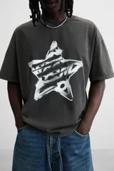 Camiseta negra con efecto lavado, cuello redondo, manga corta y estampado de estrella con texto en el centro.
