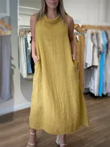 Vestido largo confeccionado en 100% lino, de diseño sin mangas y cuello buche. Presenta un corte holgado con bolsillos laterales funcionales.