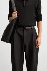 Pantalón negro de corte amplio, con pliegues en la parte delantera, bolsillos laterales y traseros de ojal.
