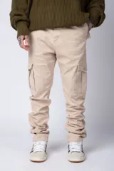 Pantalón cargo color beige con bolsillos laterales con solapa y botón. Corte ajustado.