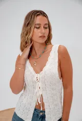 Top blanco de hilo tejido con escote en V y cierre frontal con lazos.
