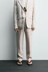 Pantalón de vestir color beige claro, confeccionado en lino, de corte recto, con bolsillos laterales y traseros.