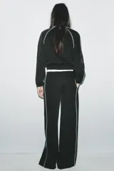 Pantalón negro capri de tiro alto con bolsillos delanteros, cintura elástica y banda lateral blanca a contraste.