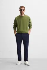 Pantalón negro de corte slim fit, confeccionado en tejido elástico. Cuenta con cintura elástica, bolsillos frontales y traseros de vivo. Cierre frontal con cremallera y botón.