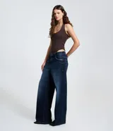 Pantalón de jean de mujer, modelo wide leg, con cintura baja tradicional, cierre por botón metálico y cremallera, y bolsillos curvos delanteros y traseros.