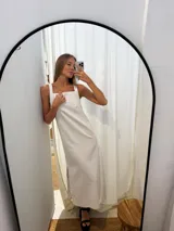 Vestido largo blanco, de corte recto, con breteles anchos y tajos laterales.