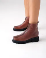 Botas cortas color marrón de cuero vacuno con suela track negra de goma. Presentan cierre lateral con cremallera YKK y puntera cuadrada.