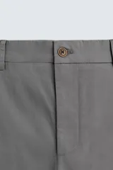 Pantalón chino color beige, de corte recto y tiro medio. Confeccionado en tejido de algodón con elasticidad, con bolsillos laterales y traseros de vivo. Cierre frontal con cremallera y botón.