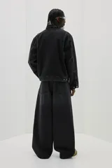Jean de denim rígido color negro, de corte holgado de cadera a bajo con piernas redondeadas superamplias y pliegues al tobillo. Cintura estándar con cierre y tiro bajo.