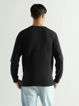 Remera negra de manga larga con cuello redondo, confeccionada en tejido mini piqué de algodón.