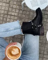 Botín de cuero vacuno negro de caña corta con hebilla y tachas plateadas.