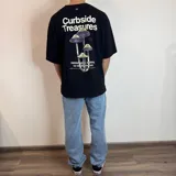 Remera negra con estampado de hongos y texto en la espalda, corte oversize.