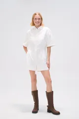 Mono corto blanco de algodón, con cuello camisero, cierre frontal con botones, mangas cortas y bolsillos.