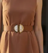 Cinturón de cuero color camel con hebilla decorativa de bronce y nácar, compuesta por dos semicírculos.