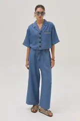 Blusa celeste de denim con cuello camisero, mangas cortas y cierre frontal con botones.