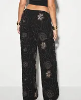 Pantalón palazzo negro con bordados de flores en color dorado.