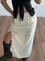 Conjunto de top negro con tirantes finos y falda larga blanca con tajo lateral.