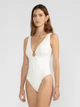 Malla enteriza blanca con escote en V y argolla metálica en el centro del busto.