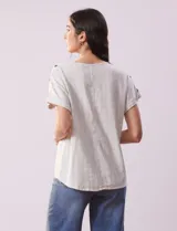 Blusa de lino color blanco con rayas verticales, de la marca Cable & Gauge. Tiene hombros con aplique de botones.