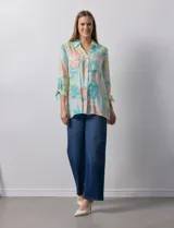 Camisa estampada con hojas en tonos celeste, naranja y verde. Tiene cuello con solapa, abertura central con botones, bolsillos aplicados en la parte delantera y mangas 3/4 con lazo.
