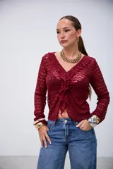 Blusa de manga larga color bordó, con tejido de punto calado, escote en V con volados y cierre frontal anudado.