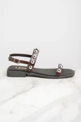 Sandalias bajas de cuero color marrón con apliques de tachas metálicas plateadas.