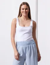 Pantalón largo de poliéster color beige con rayas verticales, pretina ancha elastizada en punto smock y pierna ancha.